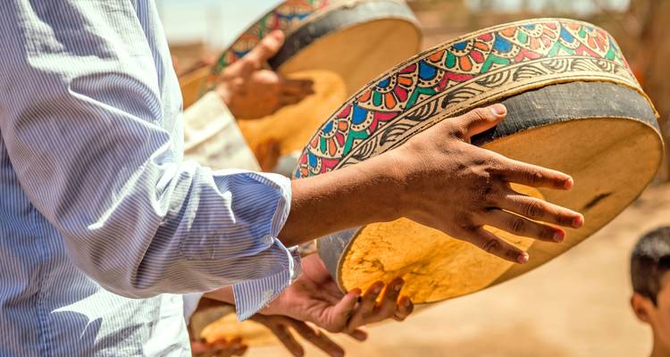 Personne jouant des instruments de percussion traditionnels dans un cadre culturel.