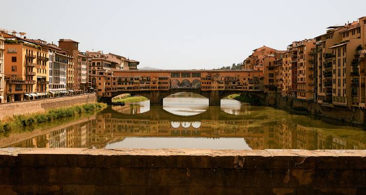 Pont du Ponte Vecchio reflété dans les eaux calmes.