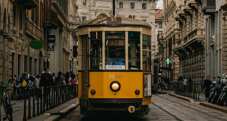 Tramway jaune classique dans une rue urbaine animée à Milan.
