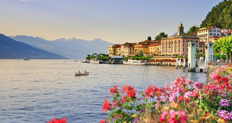 Belle scène de lac avec des fleurs et des montagnes au loin.