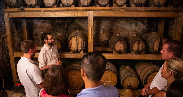 Des personnes écoutant un guide touristique dans une cave à vin.