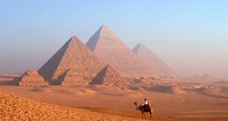 Des pyramides dans un désert avec une personne sur un chameau.
