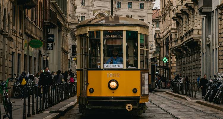 Tramway vintage jaune sur une rue de ville avec des gens qui marchent.