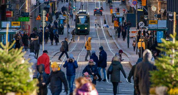 Scène de rue urbaine animée avec tramways et piétons.