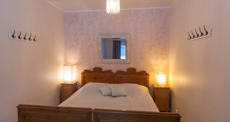 Einfaches Schlafzimmer mit Holzmöbeln und rosa Tapete.