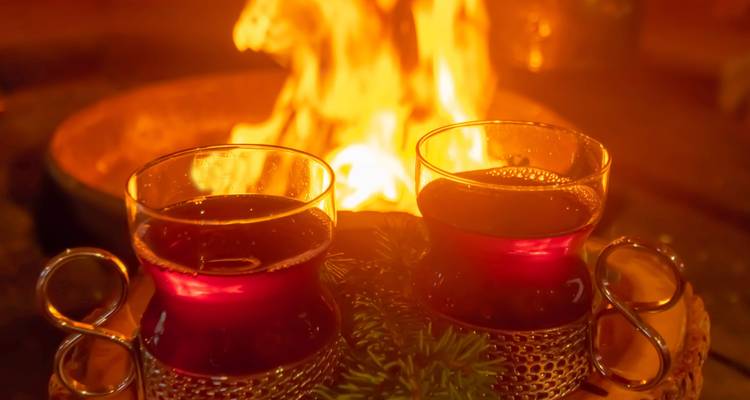 Zwei Gläser mit rotem Getränk in der Nähe eines Feuers.