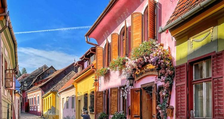 Bunte Straße mit pastellfarbenen Gebäuden und Blumenschmuck.