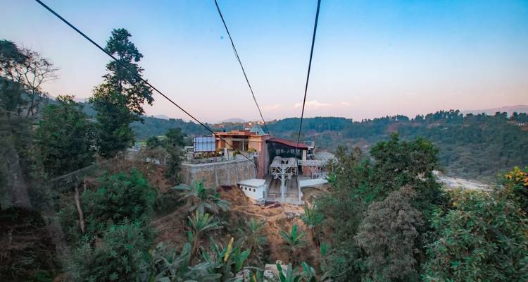 Kabelbaan station boven een bebost gebied en heuvels.