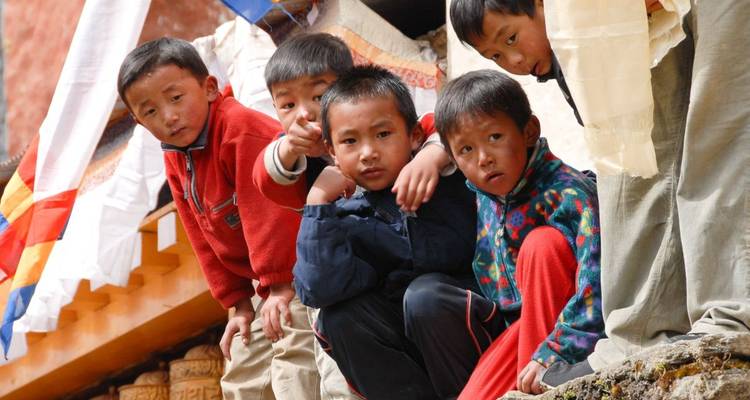 Groep kinderen die buiten spelen met traditionele gebouwen in de buurt.