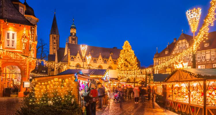 Verlichte kerstmarkt met mensen die langs de kraampjes kijken.