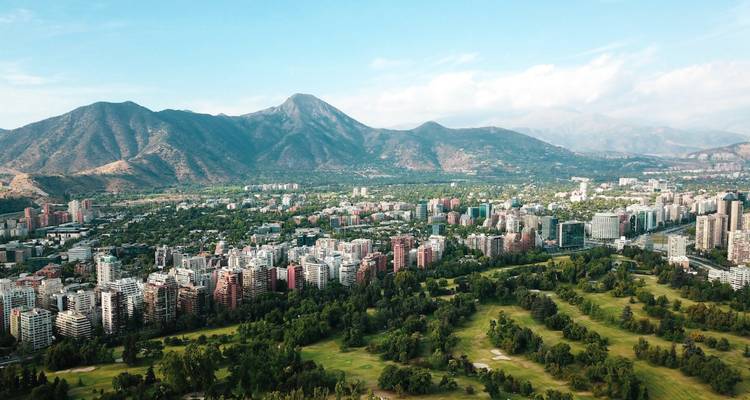 Groen stadslandschap met bergen op de achtergrond.