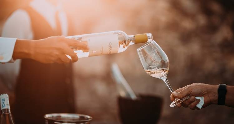 Persoon die witte wijn in een glas schenkt.