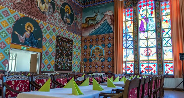 Intérieur d'une pièce colorée avec des vitraux et des peintures classiques.