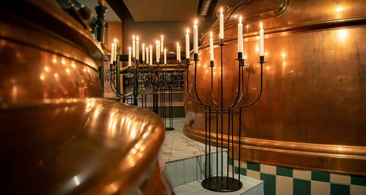 Bougies éclairant une pièce avec de grandes cuves en cuivre.