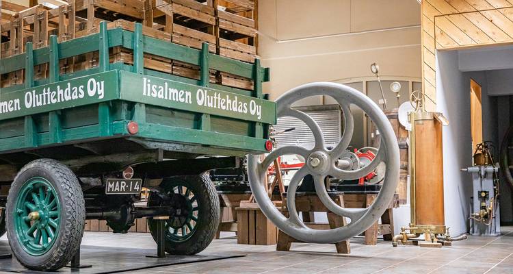 Ancien chariot en bois avec grande roue en métal exposé.