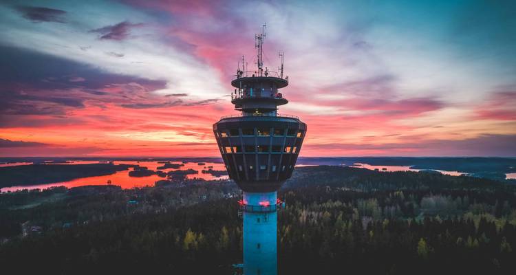 Grande tour avec antennes contre un ciel de coucher de soleil coloré.