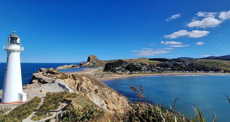 Vuurtoren met uitzicht op een kuststrand met huizen.