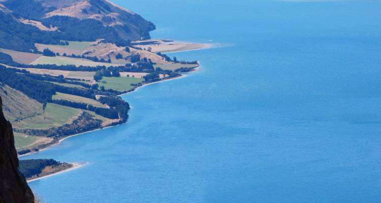Kustlijnzicht met blauwe zee en groen.