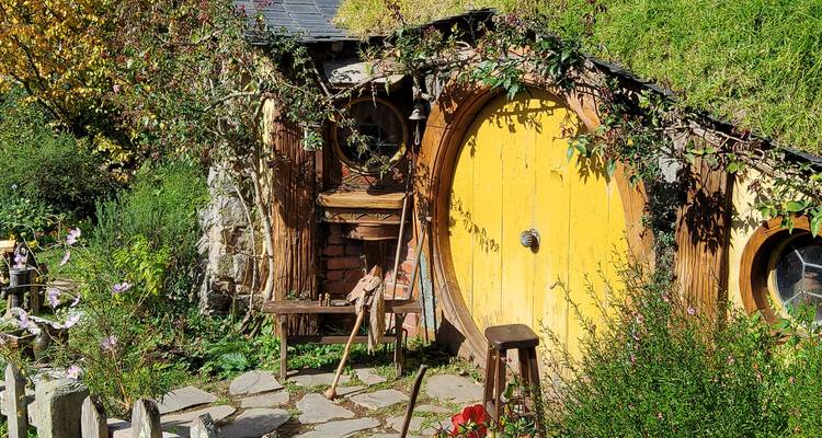 Charmant hobbit-achtig huis met een gele deur omringd door groen.