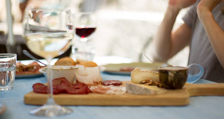 Plateau de charcuteries, fromages et vin sur une table.