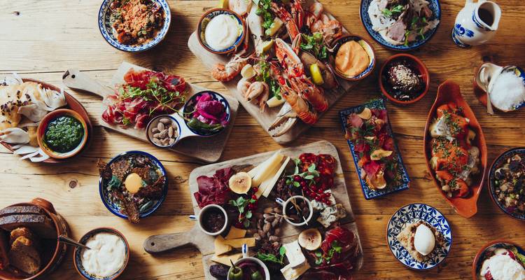 Variété de plats sur une table en bois avec du poisson, des légumes et des sauces.