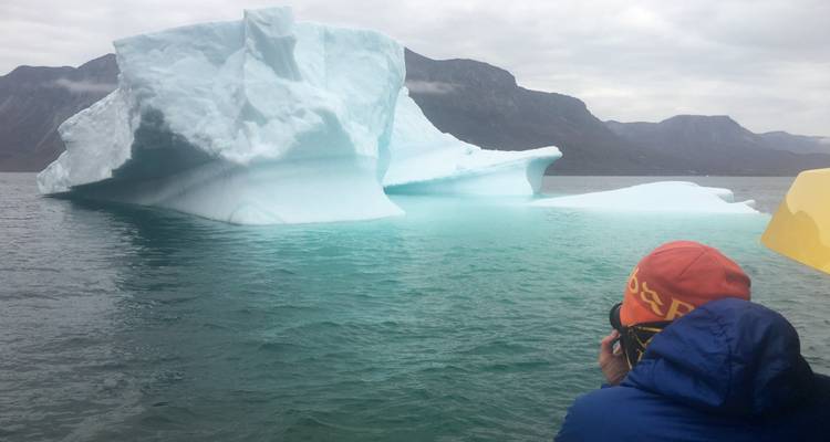 Personne photographiant un iceberg depuis un bateau.