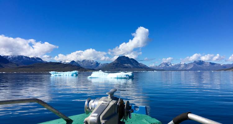 Ciel bleu dégagé se reflétant sur un fjord glacé.