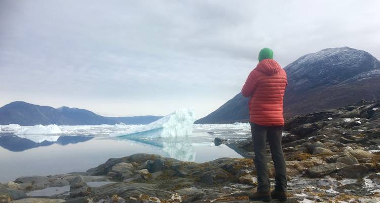 Personne sur un terrain rocheux observant de la glace flottante dans un fjord.
