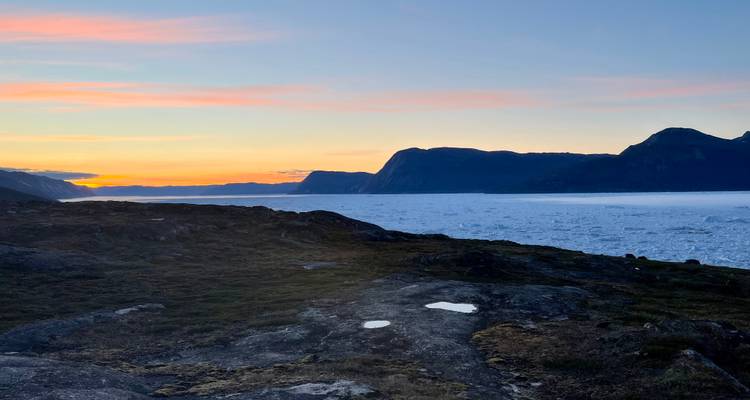 Frozen landscape and mountains during dusk.