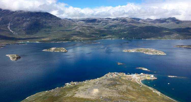 Aerial view of a coastal village with surrounding mountains in clear weather.
