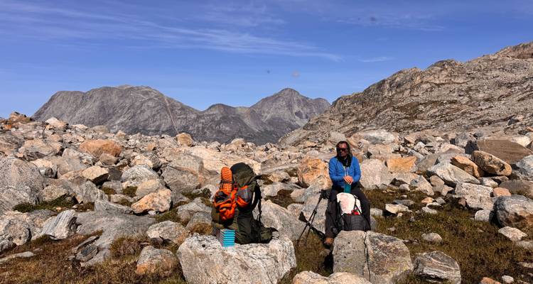Two people resting among rocks in a mountainous area.