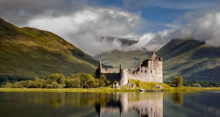 Une ruine de château ancien au bord d'un loch avec des montagnes.