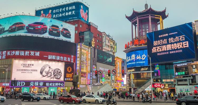 Scène de rue urbaine animée avec de grands immeubles et des enseignes au néon.