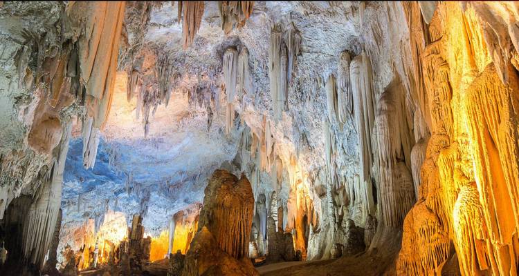 Interieur van een grot met stalactieten en kleurrijke verlichting.