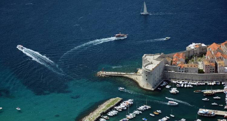 Luchtfoto van een ommuurde stad en jachthaven, boten in het water.