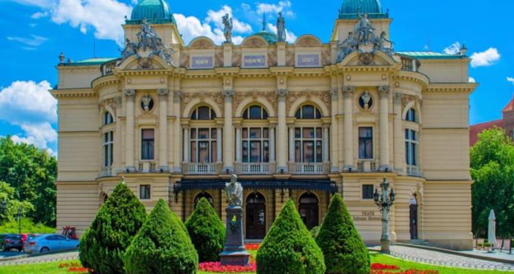 Bâtiment de théâtre historique avec jardins entretenus devant.