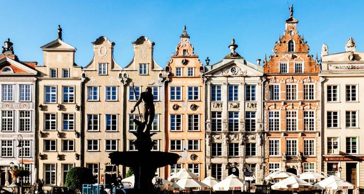 Façades colorées de bâtiments historiques avec une fontaine devant.
