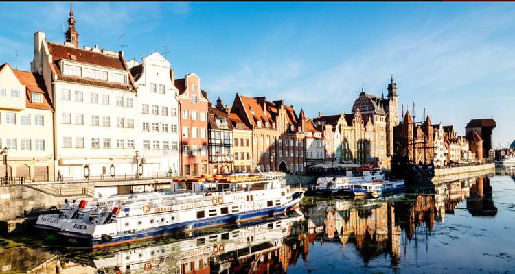 Paysage urbain avec bateaux sur un canal et façades historiques.
