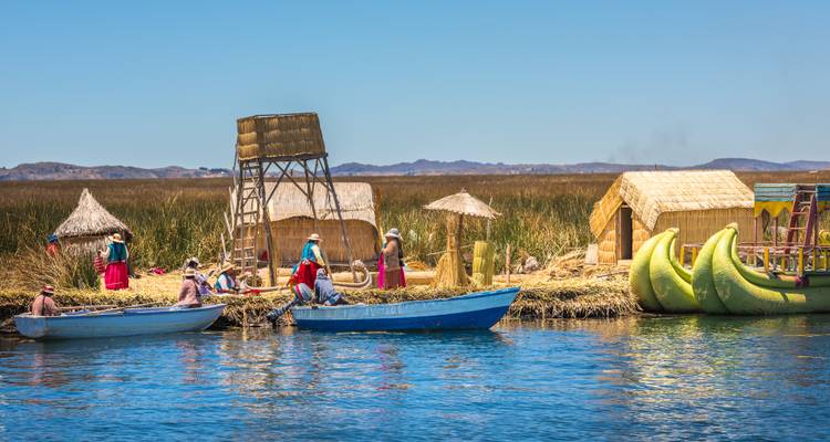Vue sur le lac avec des bateaux traditionnels en roseau et des maisons.