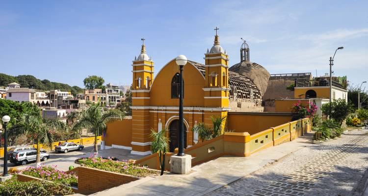 Sonnige Aussicht auf eine gelbe Kirche aus der Kolonialzeit, die auf die Straßen des Viertels Barranco blickt.