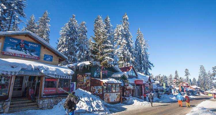 Village de ski avec des magasins et des gens qui marchent dans la neige.