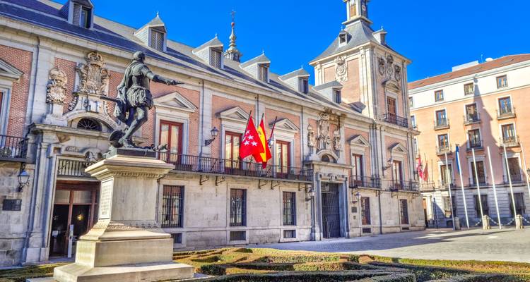 Exterior view of a historic building with columns and flags in Madrid.