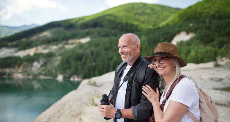 Stel met verrekijker die uitkijkt over een schilderachtig uitkijkpunt.