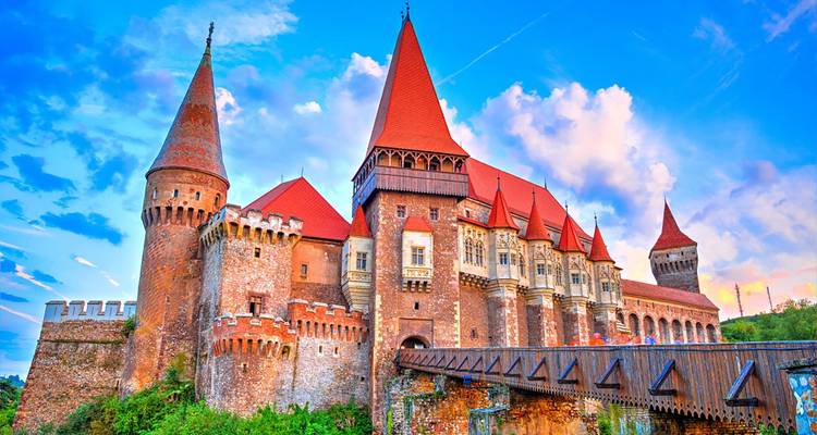 Large castle with red-tiled roofs set against a vibrant sky.
