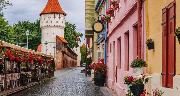 Charming street with cobblestones, colorful buildings, and a tower.