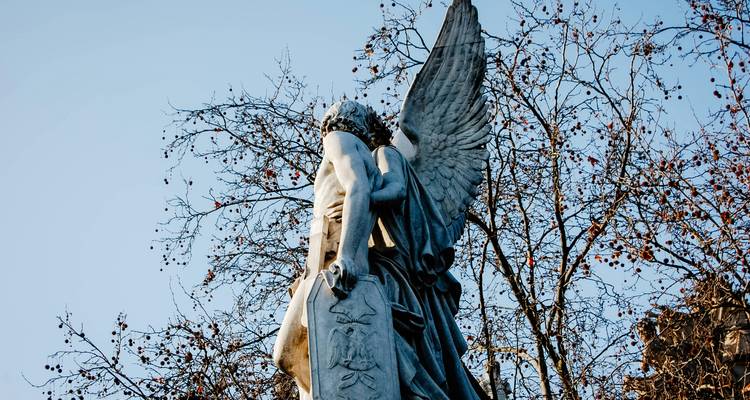 Statue d'un ange avec des arbres en arrière-plan.