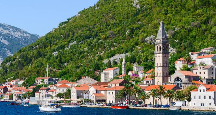 Kustplaats met een prominente kerktoren en boten op het water.
