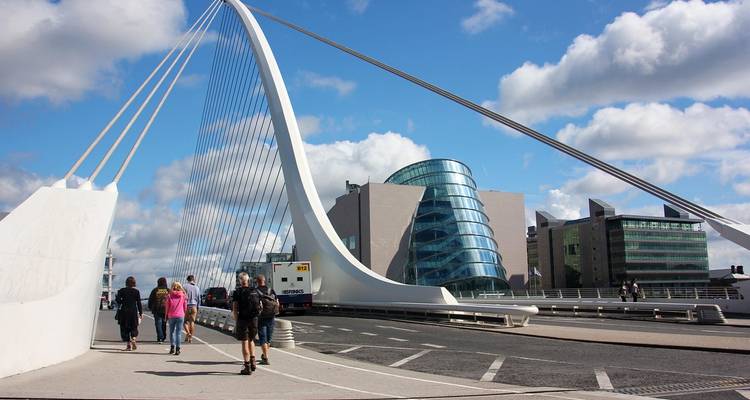 Puente moderno con peatones y edificios contemporáneos.