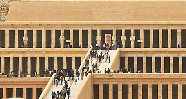 Visiteurs au Temple funéraire d'Hatchepsout avec des statues et un large escalier.