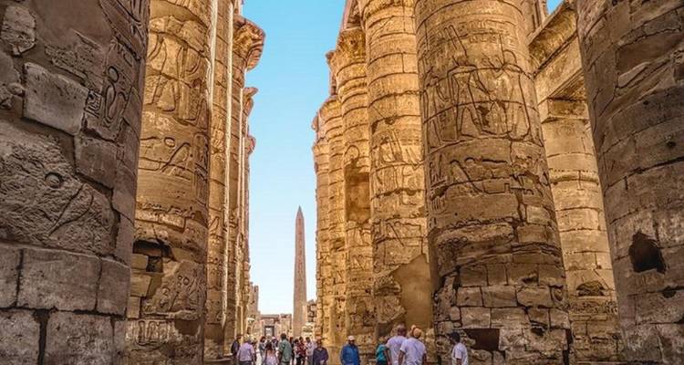 Des visiteurs explorant le vaste complexe du temple de Karnak avec ses hautes colonnes.